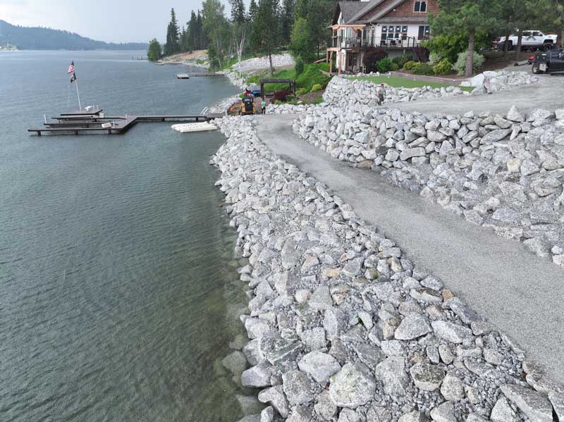 large grey multilevel pathway made of rocks leading down to a boatdock in the river