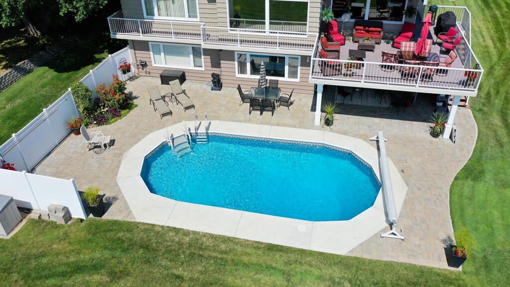 backyard area aerial view with a pool and an upper outdoor deck with lots of lawn chairs