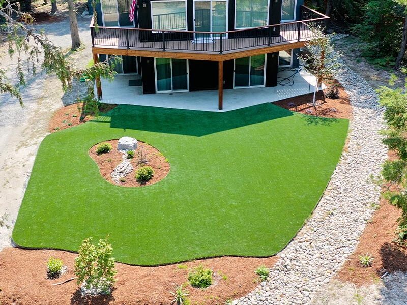 backyard area with a black house and a green turf lawn