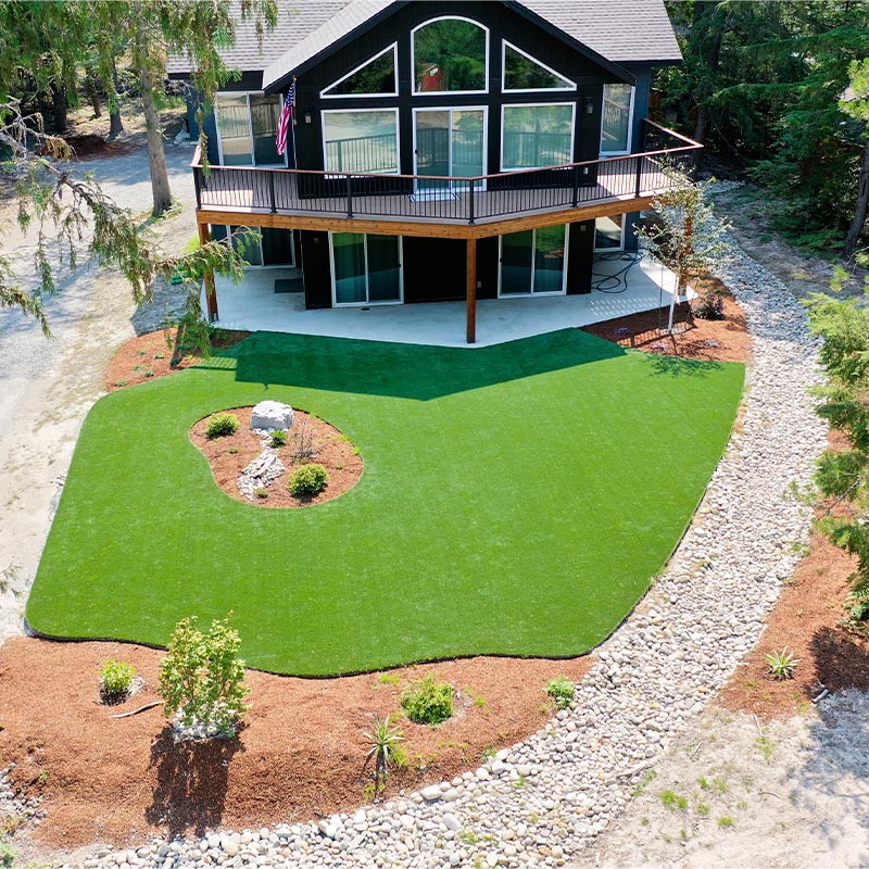 backyard area with a black house and a green turf lawn