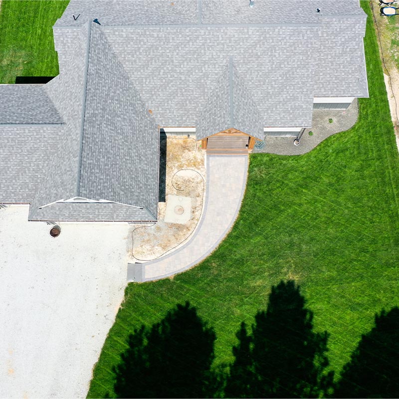 aerial view of a front yard with a gray house and a green lawn