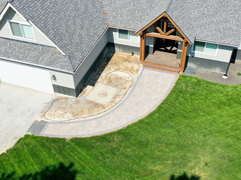 aerial view of a front yard with a gray house and a green lawn