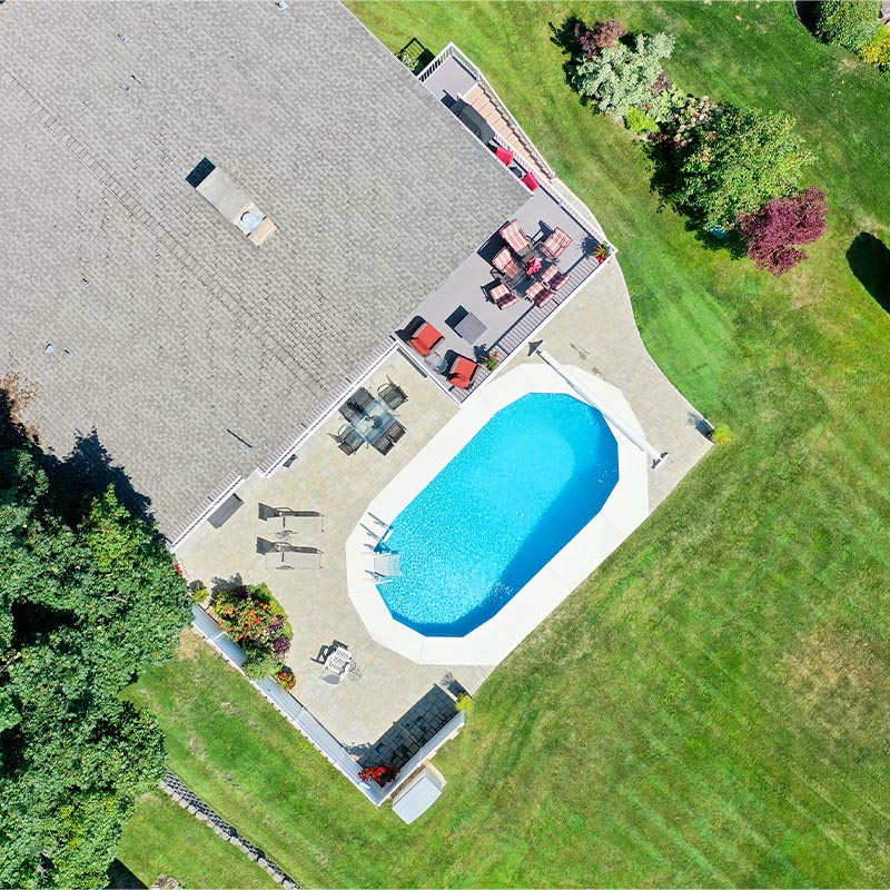 backyard area aerial view with a pool and an upper outdoor deck with lots of lawn chairs