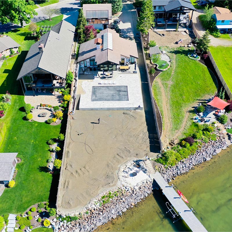 aerial view of a back yard with multiple houses and a backyard lawn ready for installation and a river at the bottom