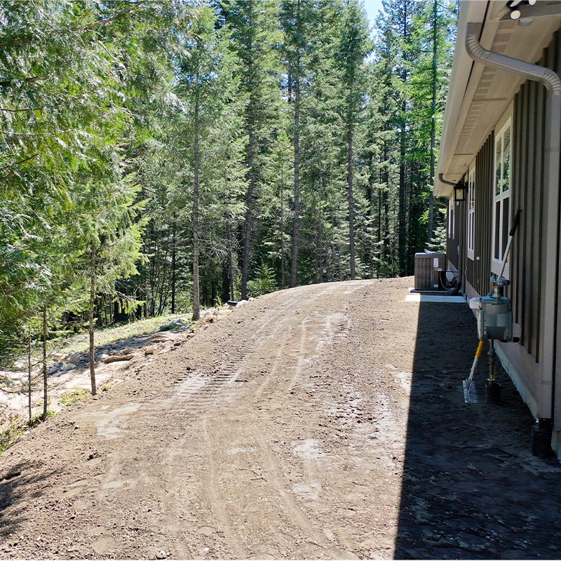 side yard area with ground prepped for lawn installation with forest in the background